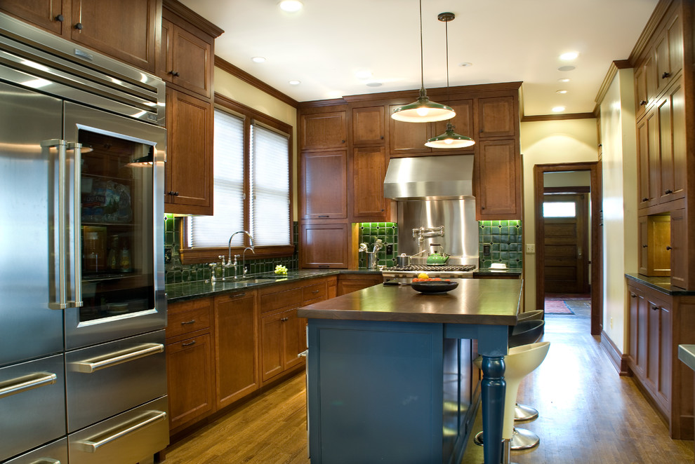 Inspiration for a mid-sized traditional l-shaped eat-in kitchen in Minneapolis with an undermount sink, recessed-panel cabinets, medium wood cabinets, soapstone benchtops, green splashback, mosaic tile splashback, stainless steel appliances, medium hardwood floors, with island, brown floor and green benchtop.