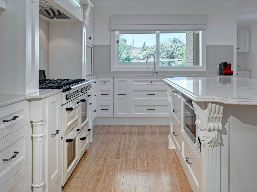 Large traditional eat-in kitchen in Other with an undermount sink, shaker cabinets, white cabinets, grey splashback, glass sheet splashback, coloured appliances, medium hardwood floors and with island.