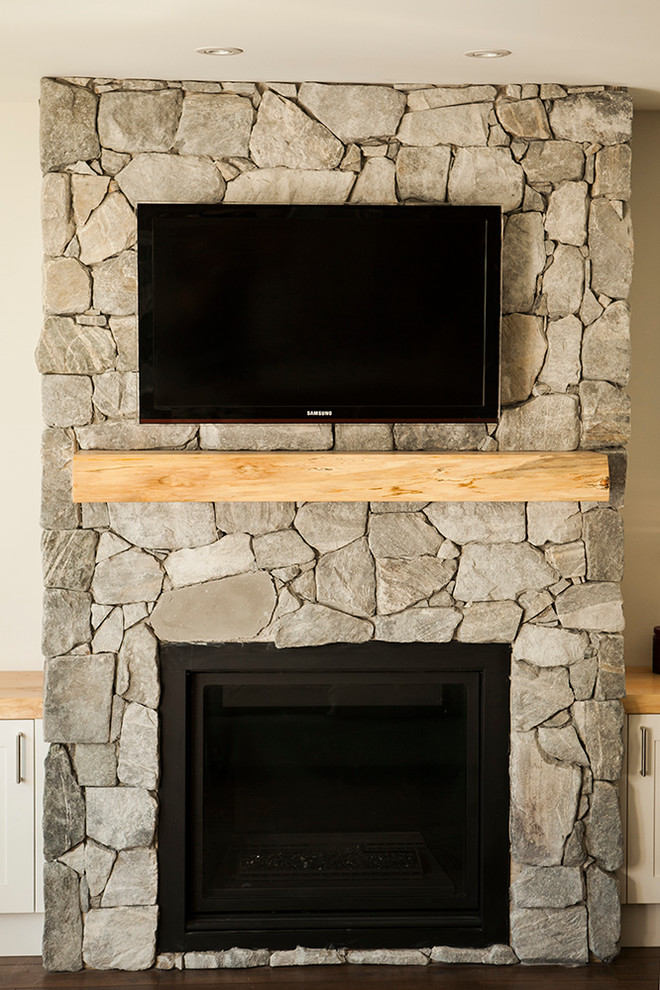 This is an example of an arts and crafts family room in Vancouver with a stone fireplace surround.