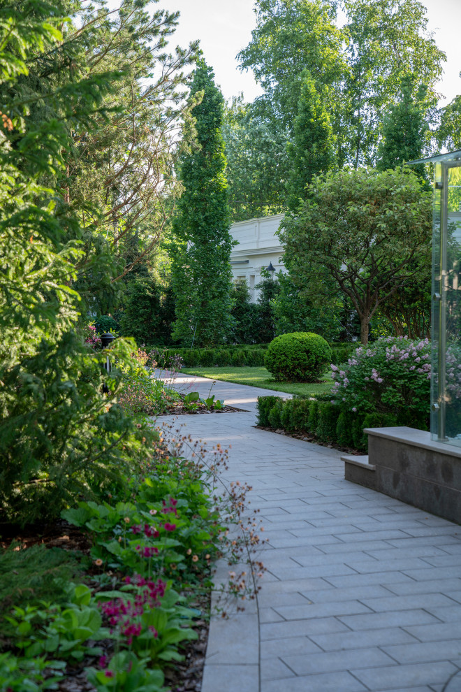 Geometrischer, Mittelgroßer, Halbschattiger Klassischer Garten im Sommer, neben dem Haus mit Blumenbeet, Natursteinplatten und Holzzaun in Moskau