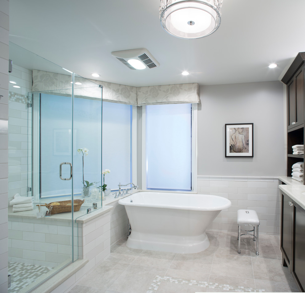 This is an example of a mid-sized transitional master bathroom in Los Angeles with an undermount sink, beaded inset cabinets, dark wood cabinets, engineered quartz benchtops, a freestanding tub, a corner shower, a two-piece toilet, white tile, glass tile, grey walls and porcelain floors.