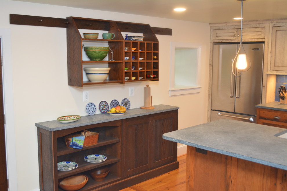 This is an example of a mid-sized country u-shaped eat-in kitchen in DC Metro with a farmhouse sink, recessed-panel cabinets, light wood cabinets, soapstone benchtops, blue splashback, ceramic splashback, stainless steel appliances, medium hardwood floors and with island.