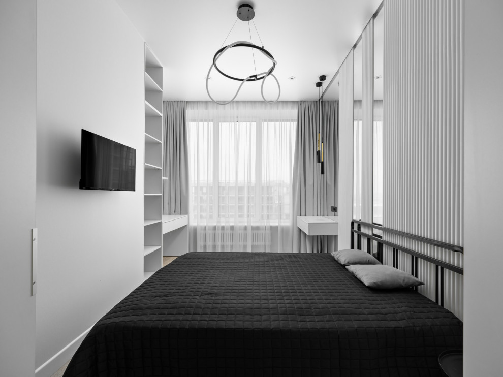 Modelo de dormitorio principal contemporáneo de tamaño medio con paredes blancas, suelo laminado y suelo beige
