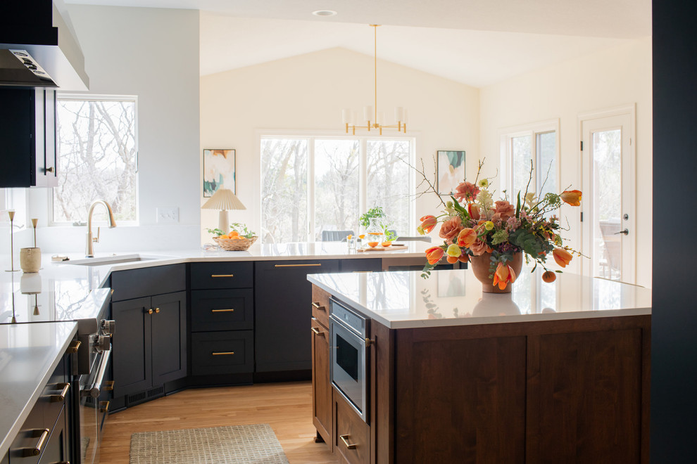 Example of a large transitional light wood floor kitchen design with an undermount sink, shaker cabinets, blue cabinets, quartz countertops, white backsplash, quartz backsplash, stainless steel appliances, an island and white countertops