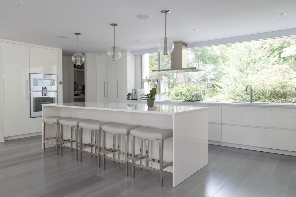 Contemporary kitchen in New York with flat-panel cabinets, white cabinets, window splashback, with island and grey floor.