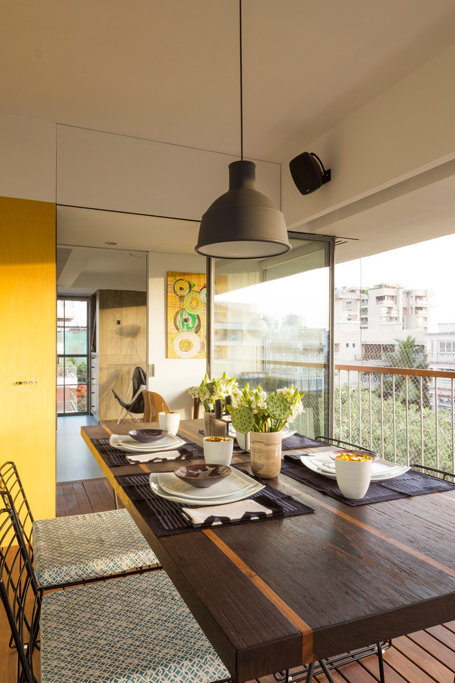 This is an example of a small contemporary dining room in Pune with yellow walls and dark hardwood floors.