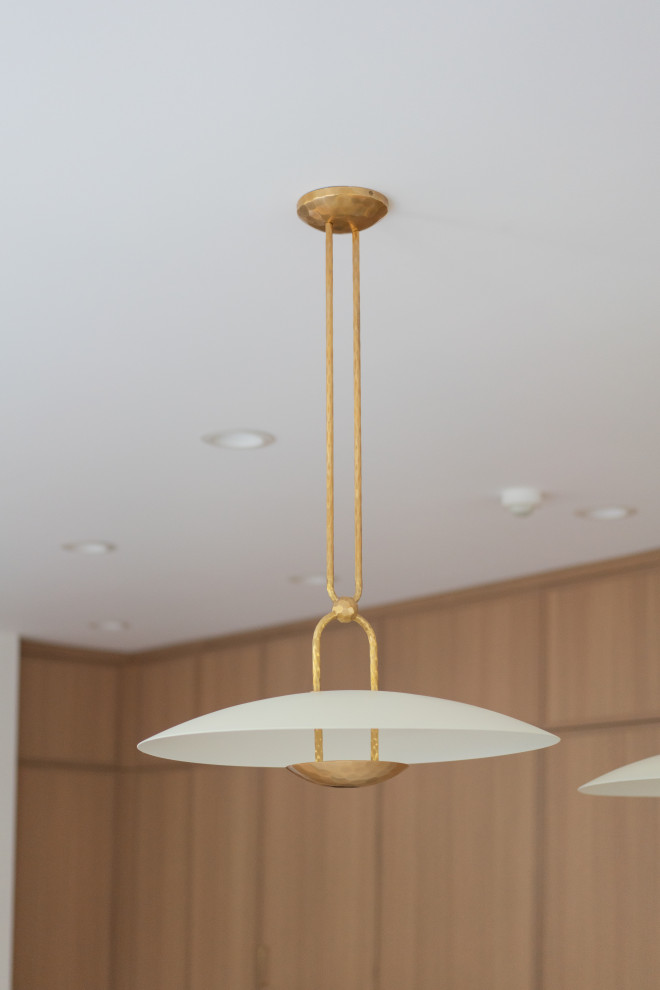 An elegant and modern kitchen faucet with a gold finish, placed near a large win