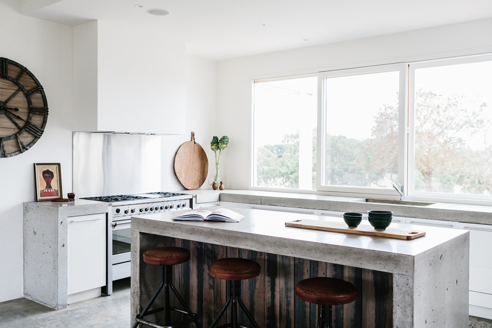 Example of a trendy concrete floor kitchen design in Geelong with an integrated sink, flat-panel cabinets, white cabinets, concrete countertops, stainless steel appliances and an island