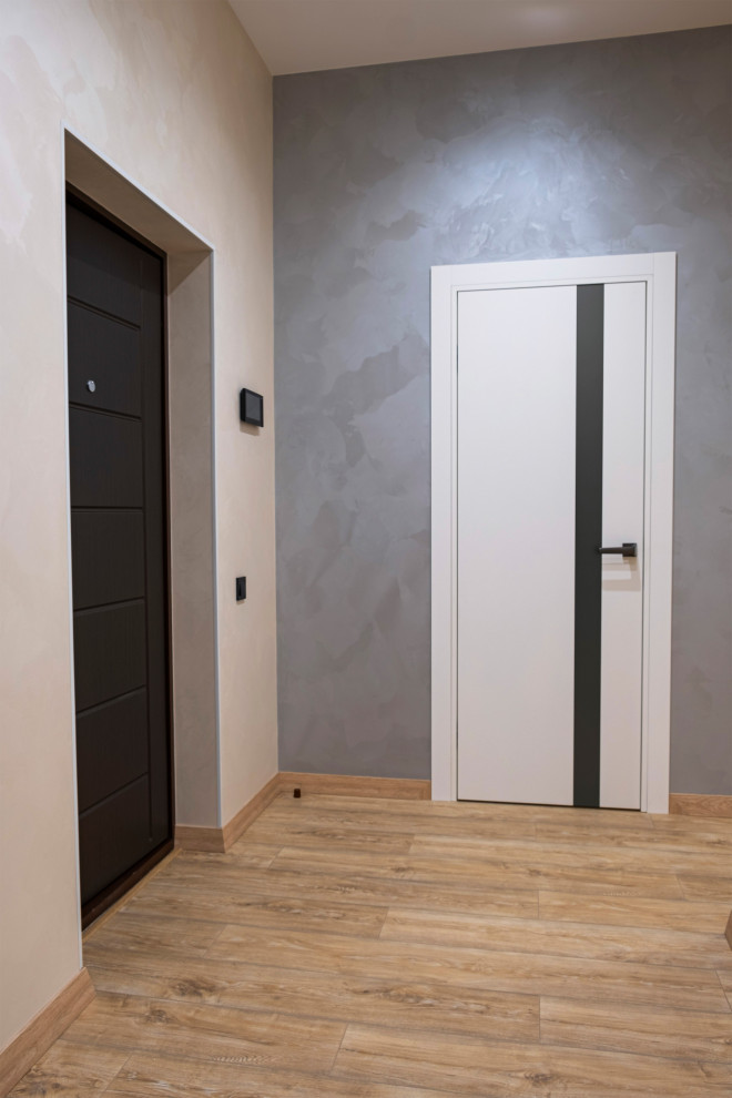 На фото: входная дверь среднего размера: освещение в современном стиле с серыми стенами, полом из ламината, одностворчатой входной дверью, черной входной дверью, коричневым полом и обоями на стенах