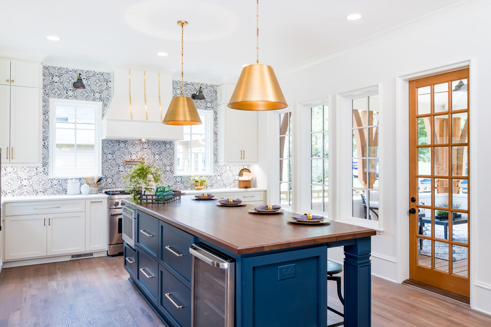 This is an example of a transitional l-shaped eat-in kitchen in Charlotte with shaker cabinets, blue cabinets, wood benchtops, multi-coloured splashback, stainless steel appliances, medium hardwood floors, with island, brown floor and brown benchtop.