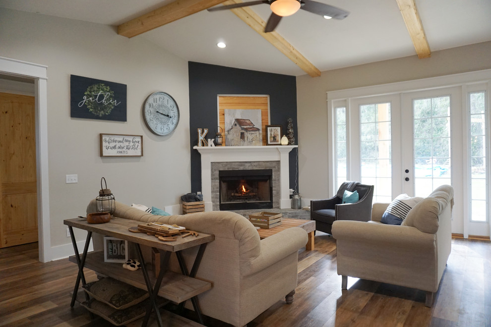 Photo of a mid-sized country open concept living room with grey walls, vinyl floors, a corner fireplace, a brick fireplace surround and brown floor.