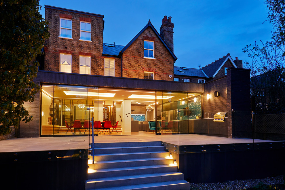 Photo of a mid-sized contemporary one-storey brick grey house exterior in London with a flat roof and a green roof.