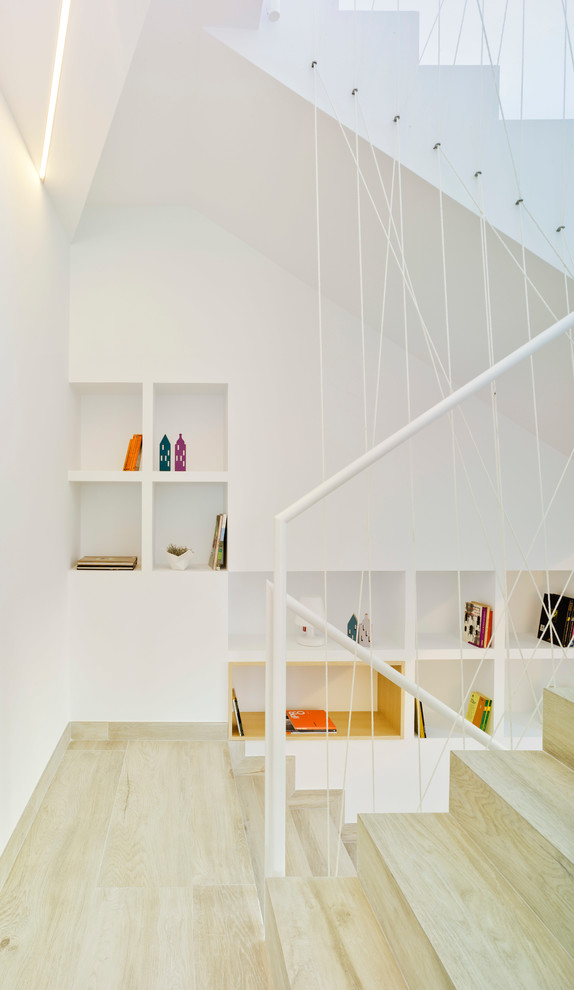 Contemporary wood u-shaped staircase in Other with wood risers and metal railing.