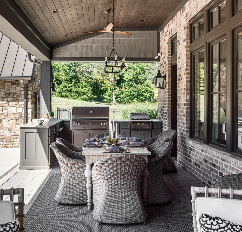 Photo of an expansive traditional backyard patio in Nashville with natural stone pavers and a roof extension.