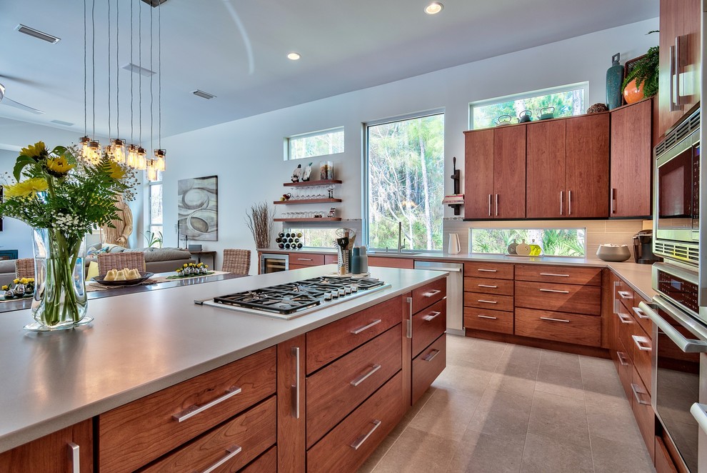 This is an example of a contemporary l-shaped open plan kitchen in Miami with flat-panel cabinets, medium wood cabinets, beige splashback, stainless steel appliances and with island.