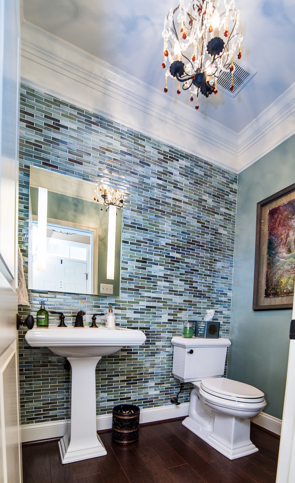 Small transitional powder room in Baltimore with a pedestal sink, a two-piece toilet, blue tile, glass tile, blue walls, dark hardwood floors and brown floor.