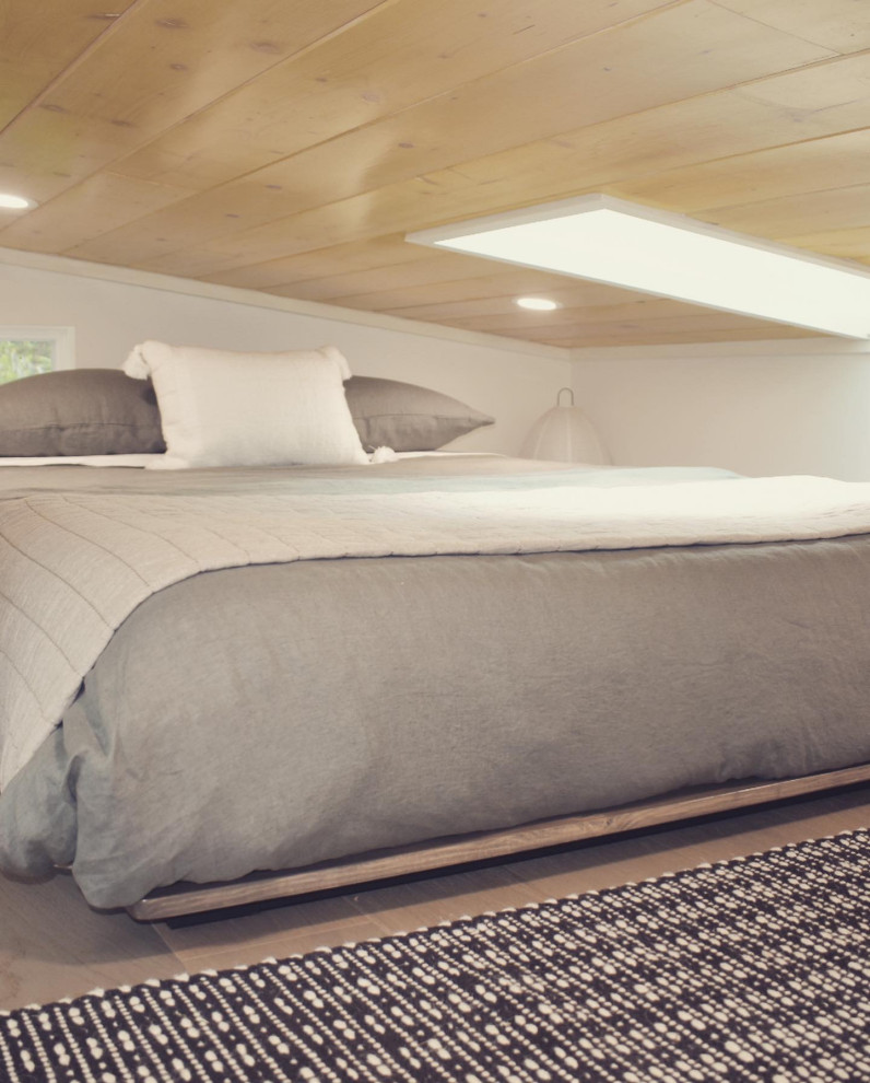 Modelo de dormitorio tipo loft contemporáneo pequeño con paredes blancas, suelo de madera clara, suelo beige y machihembrado