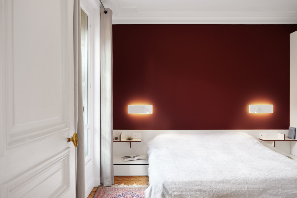 Mid-sized contemporary master bedroom in Paris with red walls and light hardwood floors.