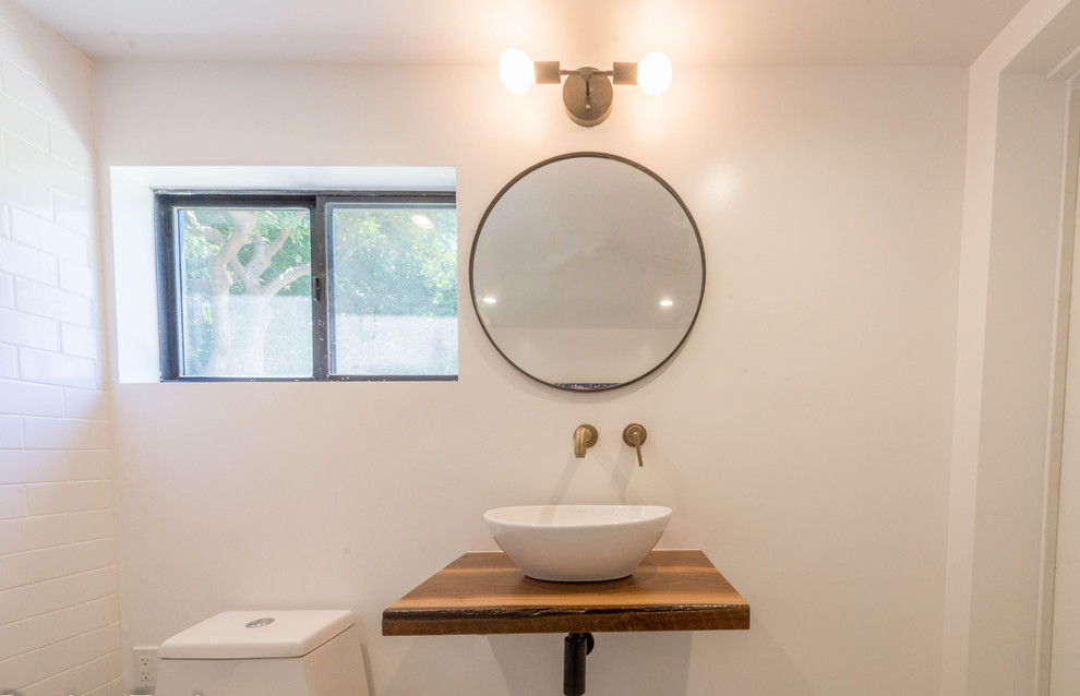 Photo of a mid-sized contemporary master bathroom in Los Angeles with medium wood cabinets, a freestanding tub, a one-piece toilet, white tile, subway tile, white walls, ceramic floors, a vessel sink, wood benchtops, multi-coloured floor, brown benchtops, a single vanity and a floating vanity.