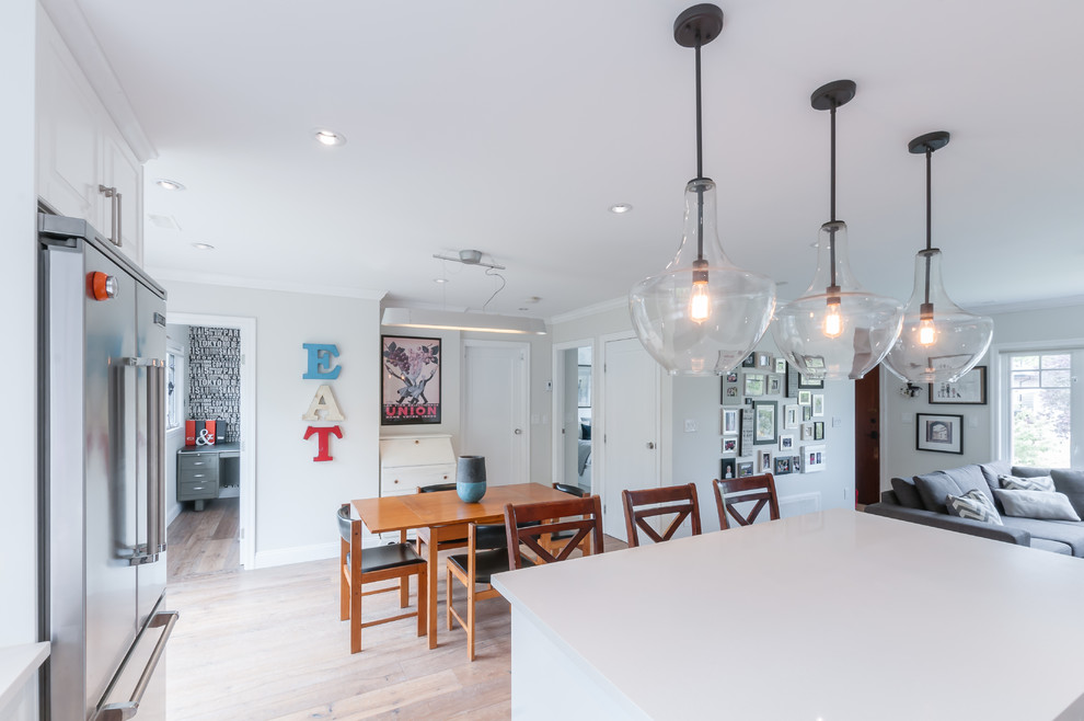 Country open plan dining in Vancouver with white walls and light hardwood floors.