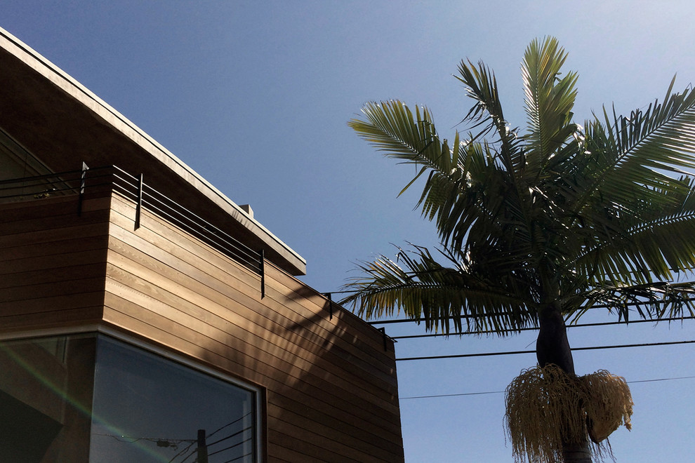 This is an example of a large tropical two-storey brown exterior in Orange County with wood siding.