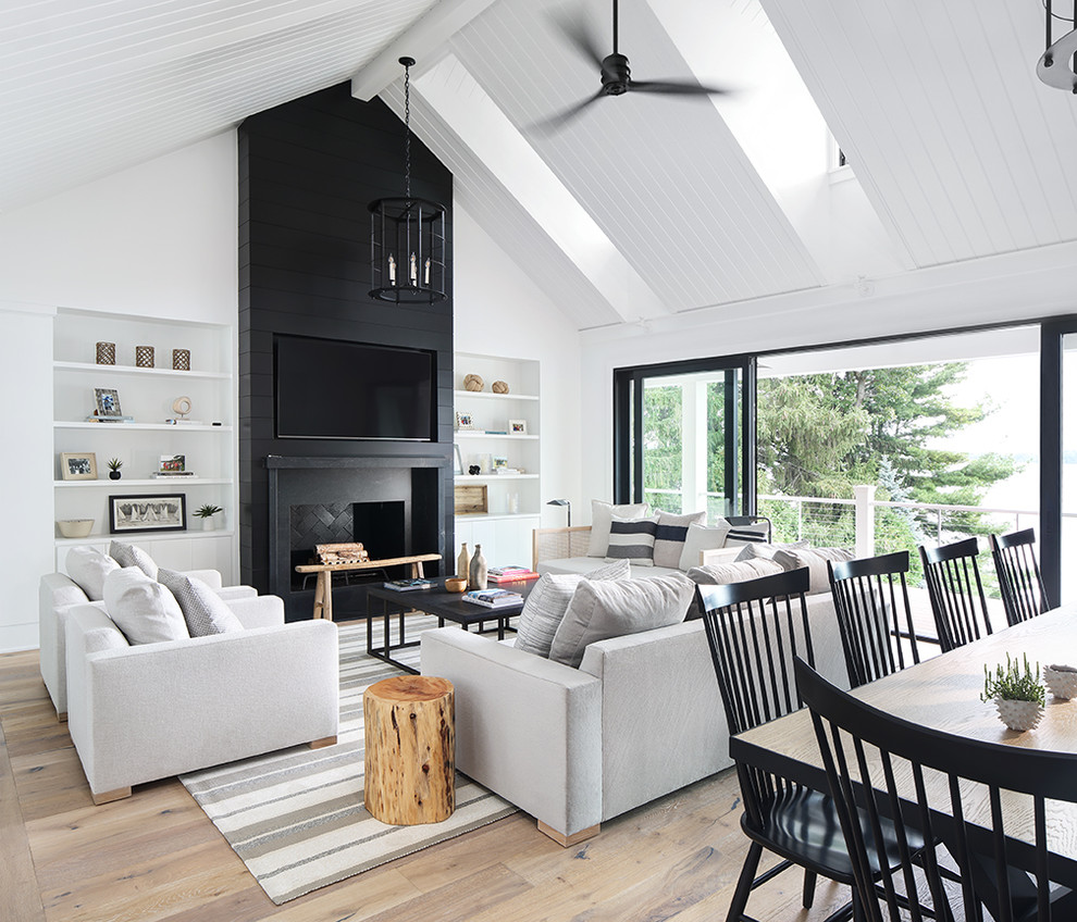 Inspiration for a country open concept living room in Milwaukee with white walls, light hardwood floors, a standard fireplace and a wall-mounted tv.