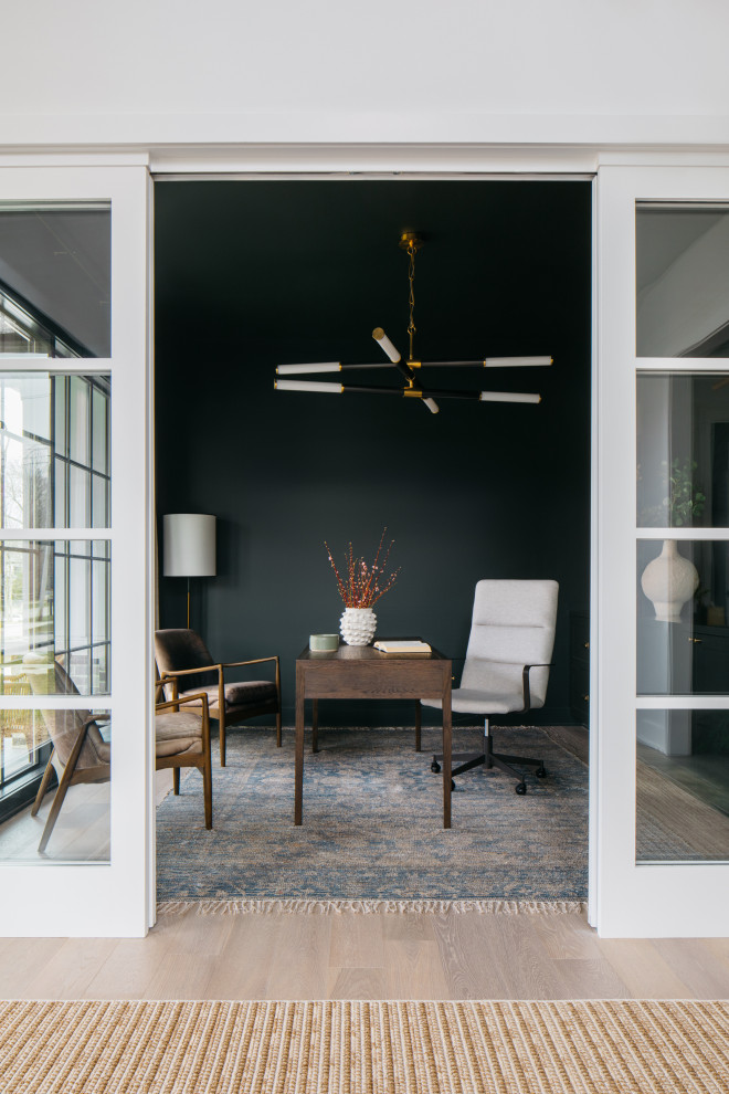 Imagen de despacho clásico renovado con paredes negras, suelo de madera clara, escritorio independiente y suelo beige