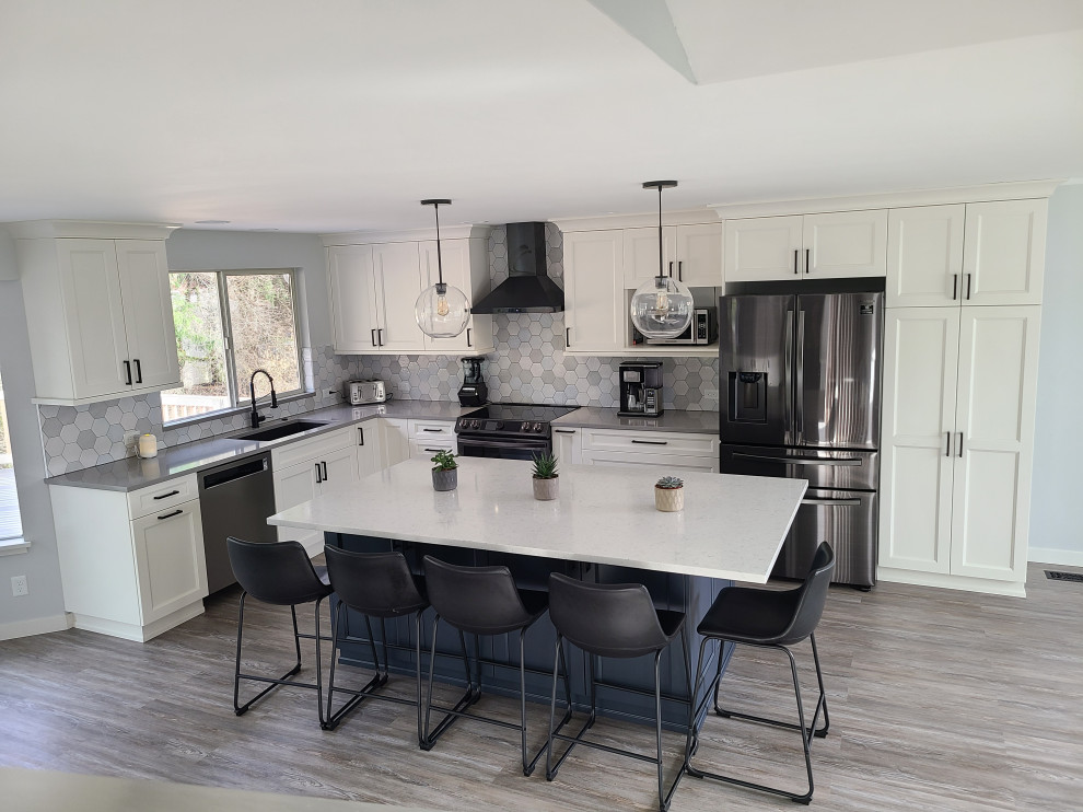 This is an example of a mid-sized transitional l-shaped eat-in kitchen in Seattle with a single-bowl sink, shaker cabinets, white cabinets, quartz benchtops, multi-coloured splashback, ceramic splashback, stainless steel appliances, laminate floors, with island, grey floor and grey benchtop.