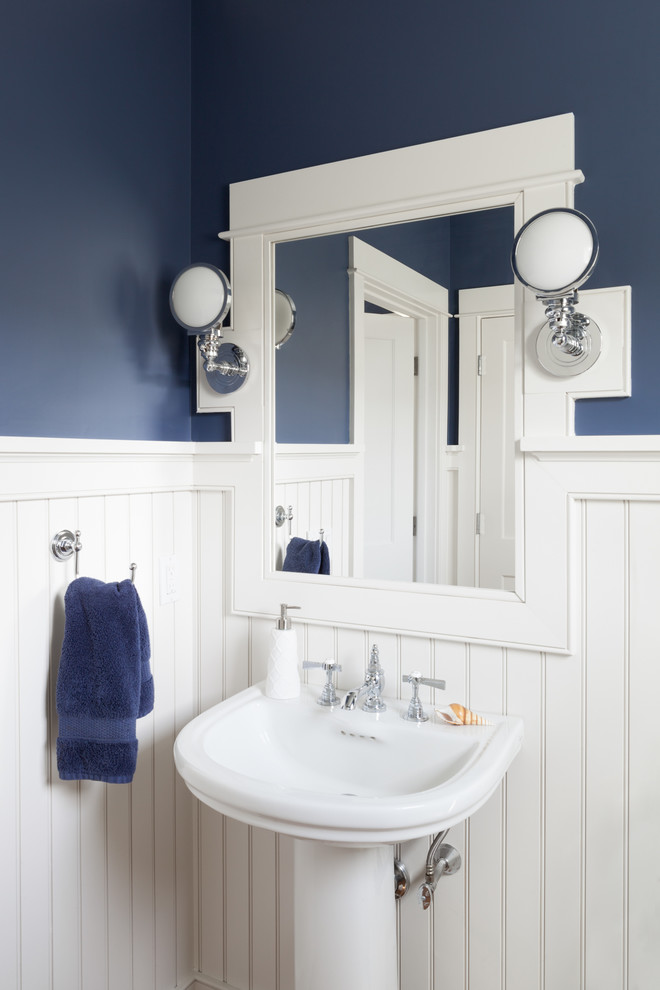 This is an example of a small beach style powder room in Boston with blue walls, medium hardwood floors, a pedestal sink and brown floor.