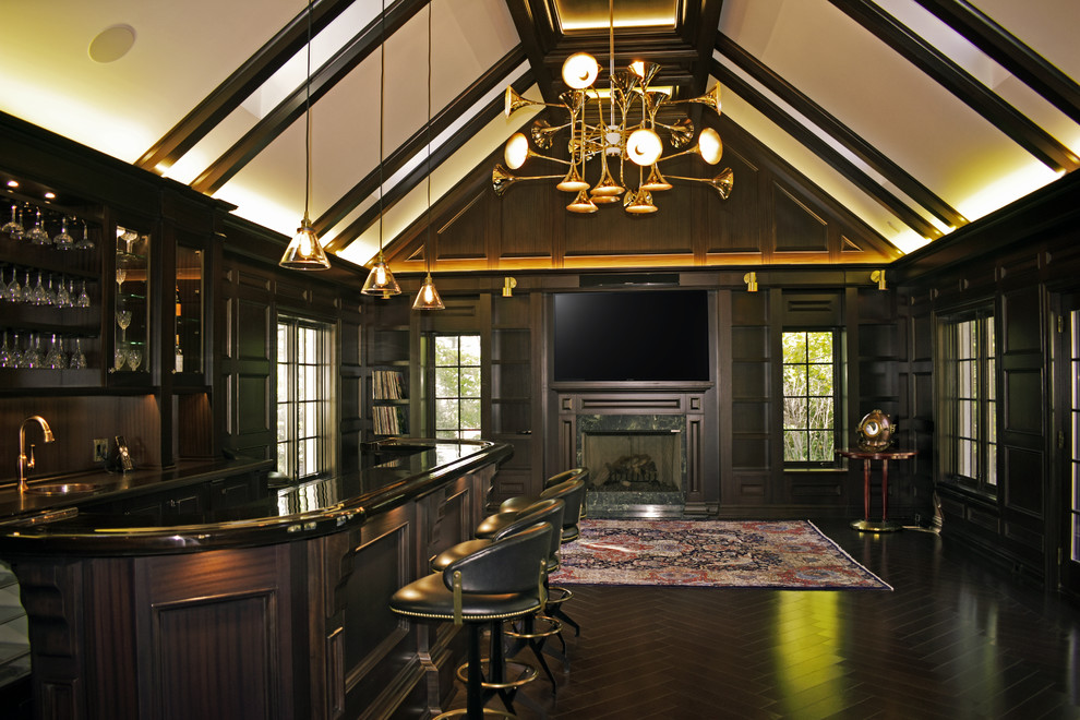 Expansive traditional u-shaped seated home bar in New York with dark wood cabinets, a drop-in sink, wood benchtops, brown splashback, timber splashback and dark hardwood floors.
