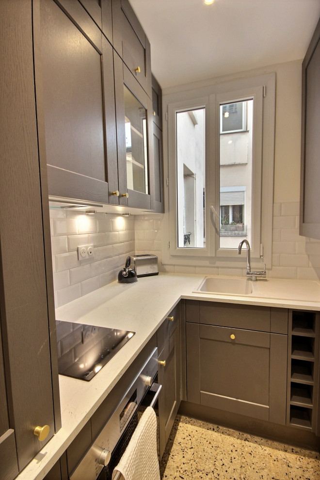 Photo of a small transitional l-shaped open plan kitchen in Paris with an undermount sink, black cabinets, marble benchtops, white splashback, brick splashback, panelled appliances, terrazzo floors, beige floor and white benchtop.