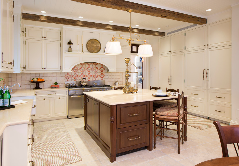 Photo of a mid-sized traditional u-shaped eat-in kitchen in New York with a farmhouse sink, white cabinets, with island, beige floor, beaded inset cabinets, marble benchtops, beige splashback, terra-cotta splashback, white appliances, limestone floors and white benchtop.