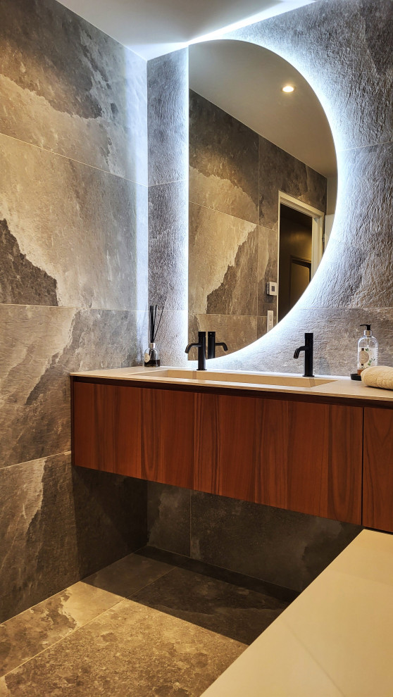 This is an example of a mid-sized contemporary powder room in Toulouse with beaded inset cabinets, dark wood cabinets, a wall-mount toilet, ceramic tile, ceramic floors, engineered quartz benchtops and beige benchtops.
