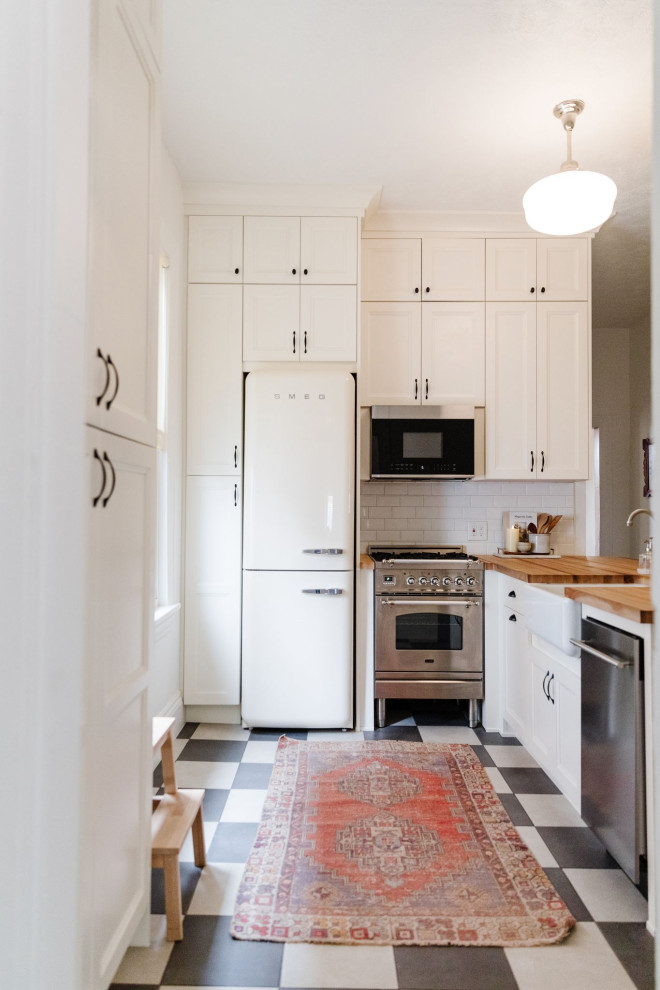 На фото: кухня в стиле шебби-шик с белыми фасадами, деревянной столешницей, разноцветным полом и коричневой столешницей