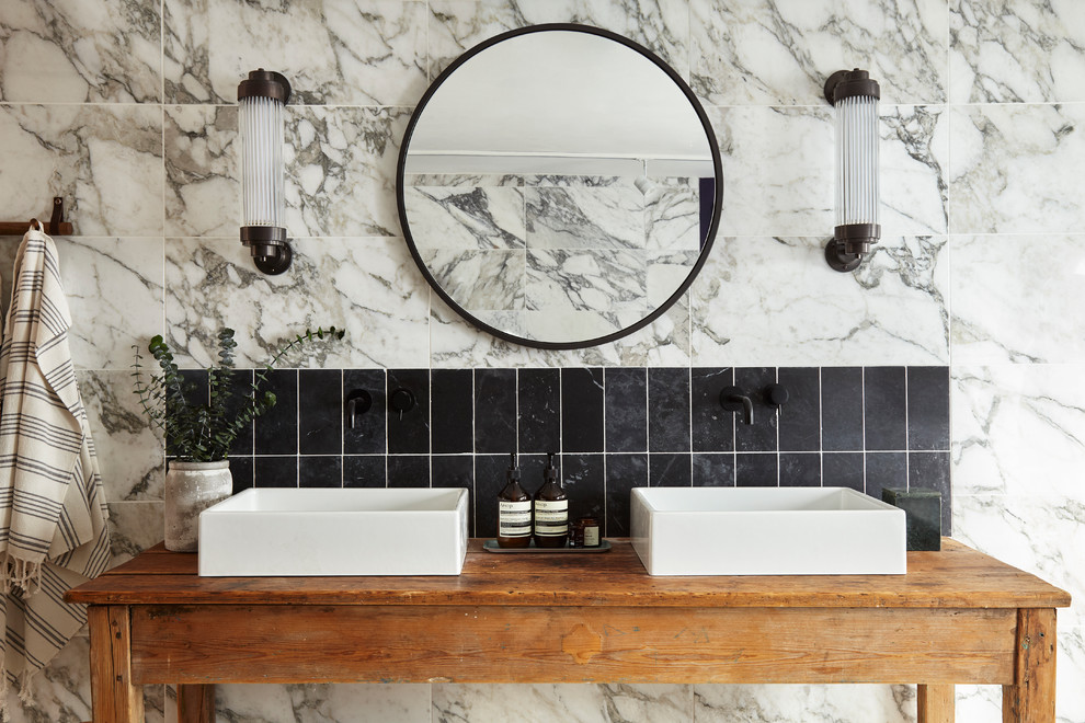 Design ideas for a mid-sized transitional bathroom in London with marble, a vessel sink, distressed cabinets, black tile, white tile and wood benchtops.