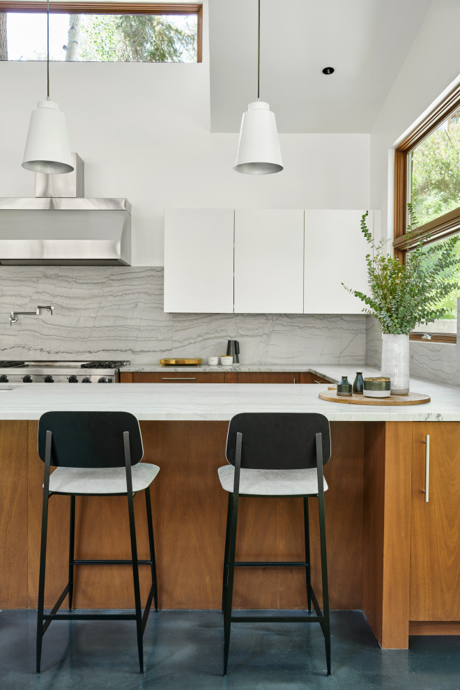 Contemporary u-shaped kitchen in Kansas City with an undermount sink, flat-panel cabinets, white cabinets, white splashback, stone slab splashback, stainless steel appliances, concrete floors, a peninsula, blue floor and white benchtop.