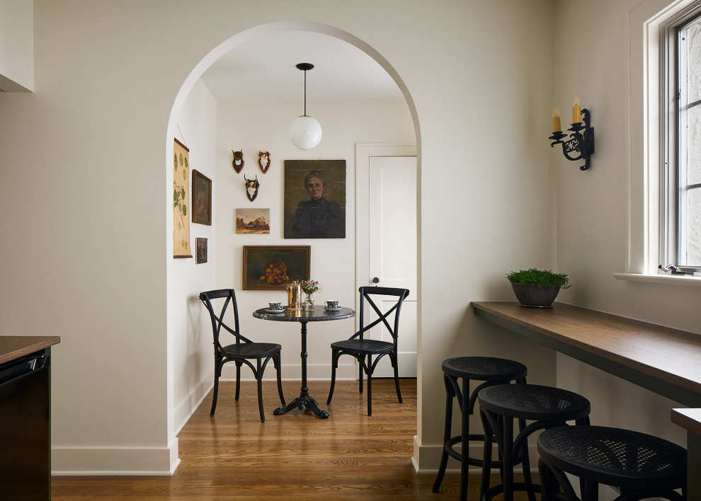 Cette photo montre une salle à manger chic de taille moyenne avec une banquette d'angle, un mur blanc, un sol en bois brun, aucune cheminée et un sol marron.