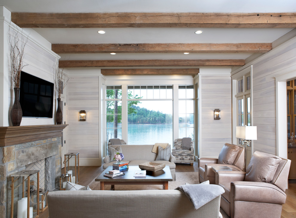 Example of a beach style medium tone wood floor family room design in Other with beige walls, a standard fireplace, a stone fireplace and a wall-mounted tv
