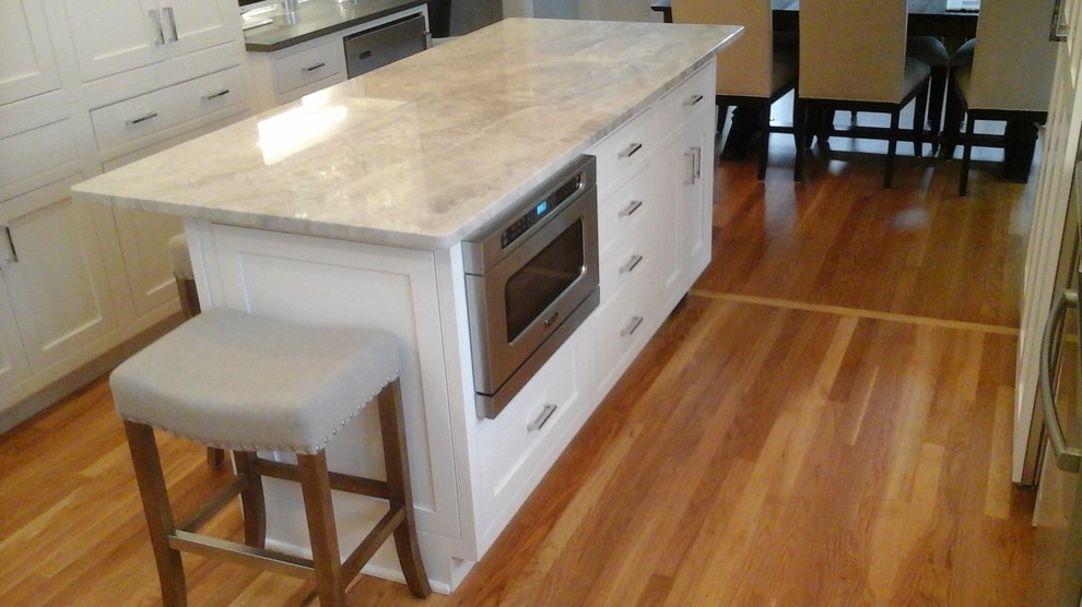 Example of a mid-sized transitional l-shaped light wood floor eat-in kitchen design in Newark with a double-bowl sink, shaker cabinets, white cabinets, solid surface countertops, multicolored backsplash, stone tile backsplash, stainless steel appliances and an island