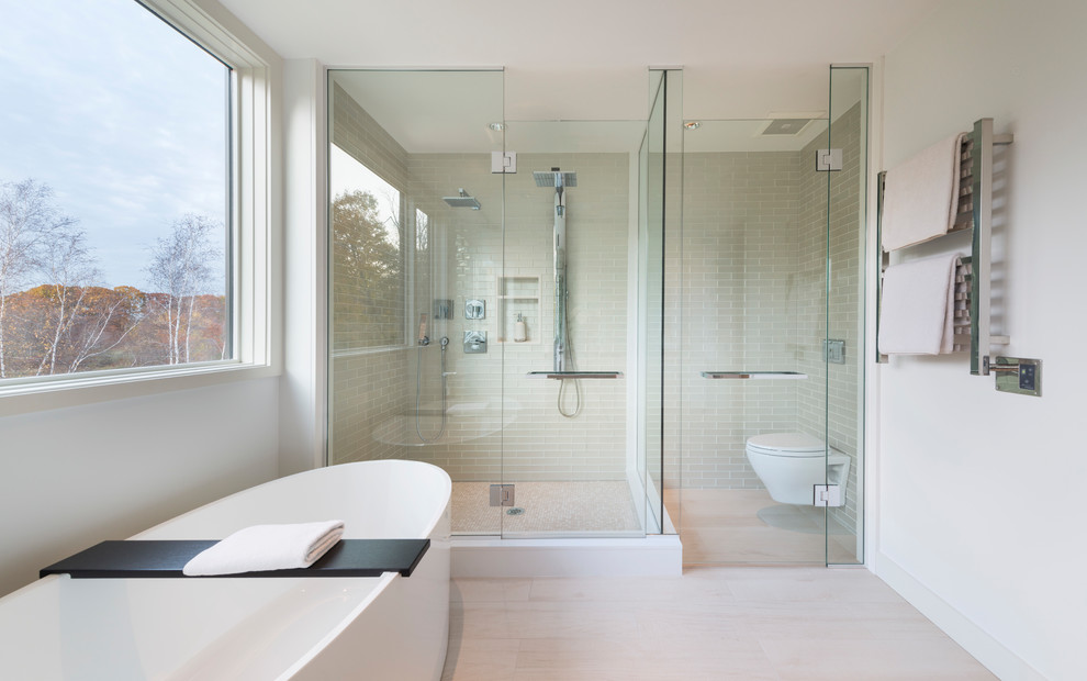 Inspiration for a large contemporary master bathroom in Boston with beaded inset cabinets, white cabinets, a freestanding tub, a corner shower, a wall-mount toilet, white tile, mosaic tile, white walls, porcelain floors, a wall-mount sink and engineered quartz benchtops.