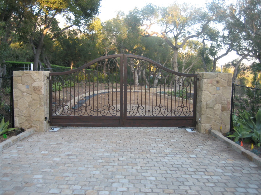This is an example of a large mediterranean front yard driveway in Los Angeles with natural stone pavers.
