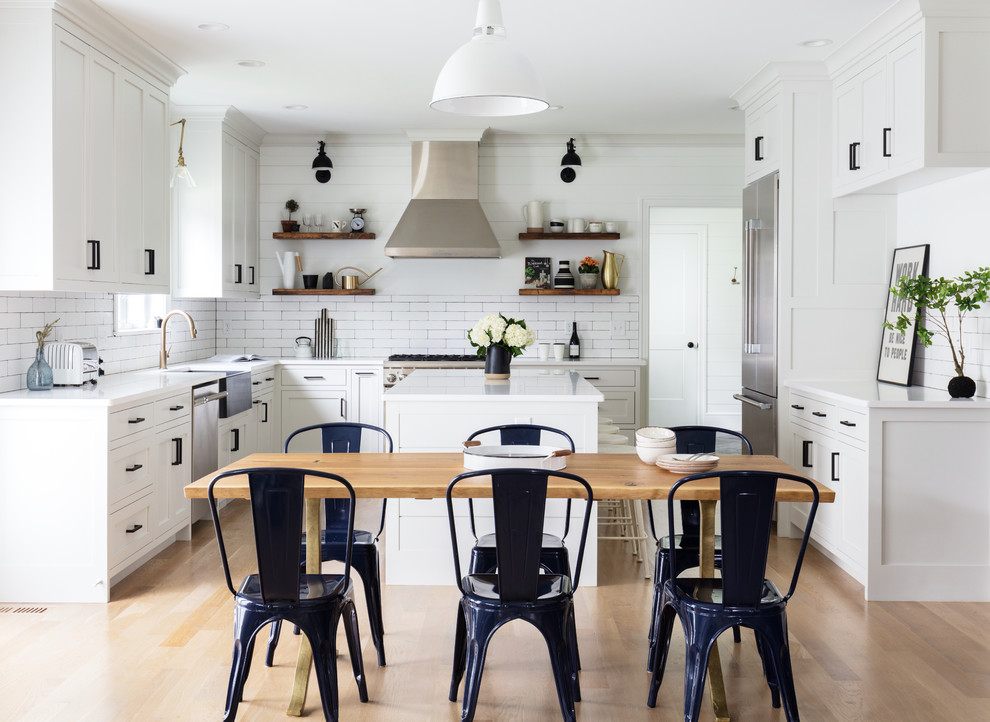 Inspiration for an expansive country u-shaped eat-in kitchen in New York with a farmhouse sink, white cabinets, white splashback, ceramic splashback, stainless steel appliances, light hardwood floors, with island, brown floor, white benchtop and shaker cabinets.