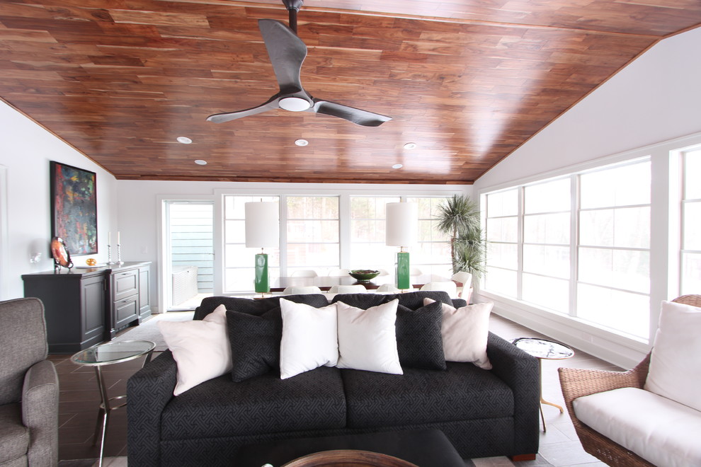 Large transitional porcelain tile and brown floor sunroom photo with a standard fireplace, a stone fireplace and a standard ceiling