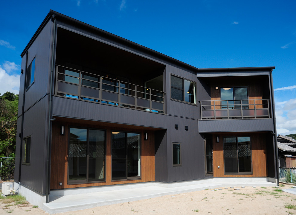 This is an example of a contemporary two-storey black exterior in Other with mixed siding and a flat roof.