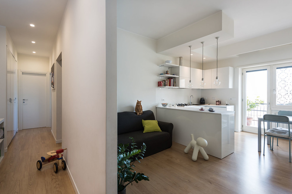 Small modern u-shaped eat-in kitchen in Rome with a drop-in sink, flat-panel cabinets, white cabinets, laminate benchtops, white splashback, stainless steel appliances, laminate floors, a peninsula and brown floor.