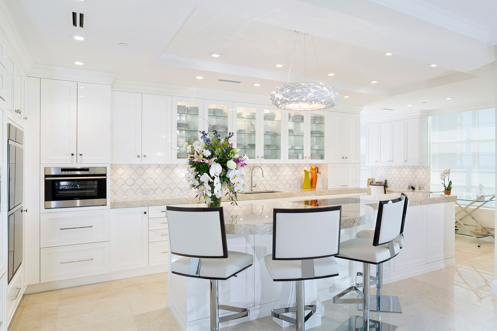 Eat-in kitchen - mid-sized transitional l-shaped porcelain tile and beige floor eat-in kitchen idea in Miami with an undermount sink, recessed-panel cabinets, white cabinets, marble countertops, beige backsplash, mosaic tile backsplash, stainless steel appliances, an island and beige countertops