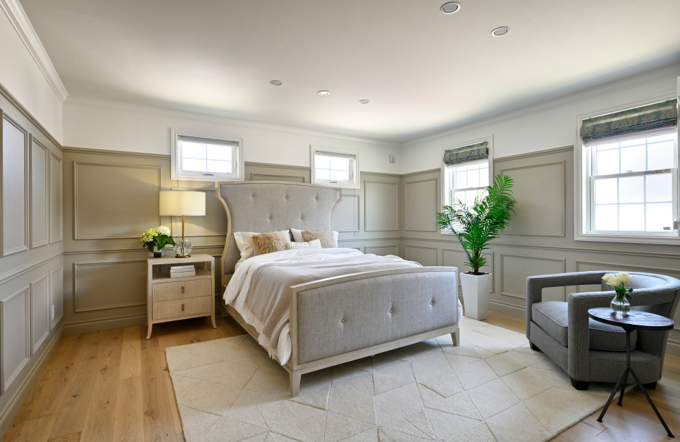 Modelo de dormitorio tradicional renovado con paredes grises, suelo de madera en tonos medios, suelo marrón y panelado