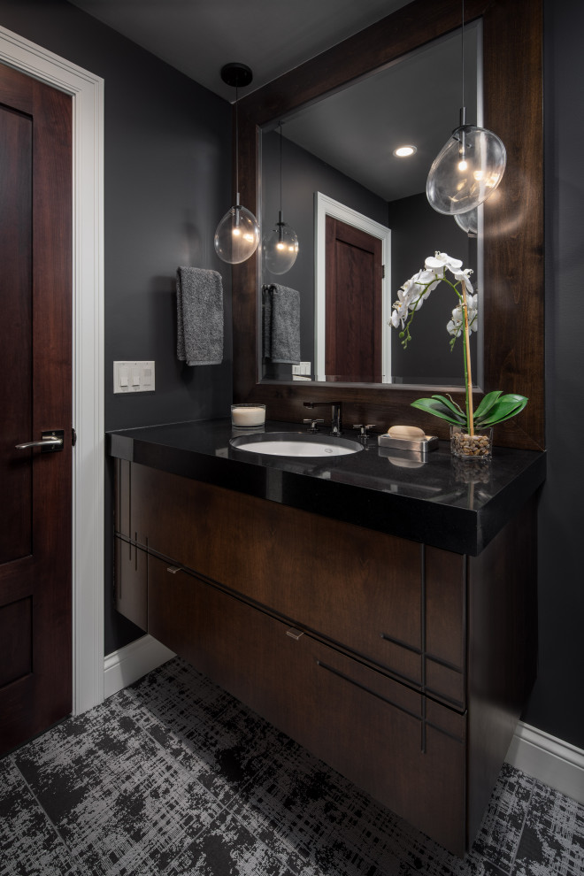 Inspiration pour un WC et toilettes design en bois brun de taille moyenne avec un placard à porte plane, un mur gris, un lavabo encastré, un plan de toilette en granite, un plan de toilette noir et meuble-lavabo encastré.
