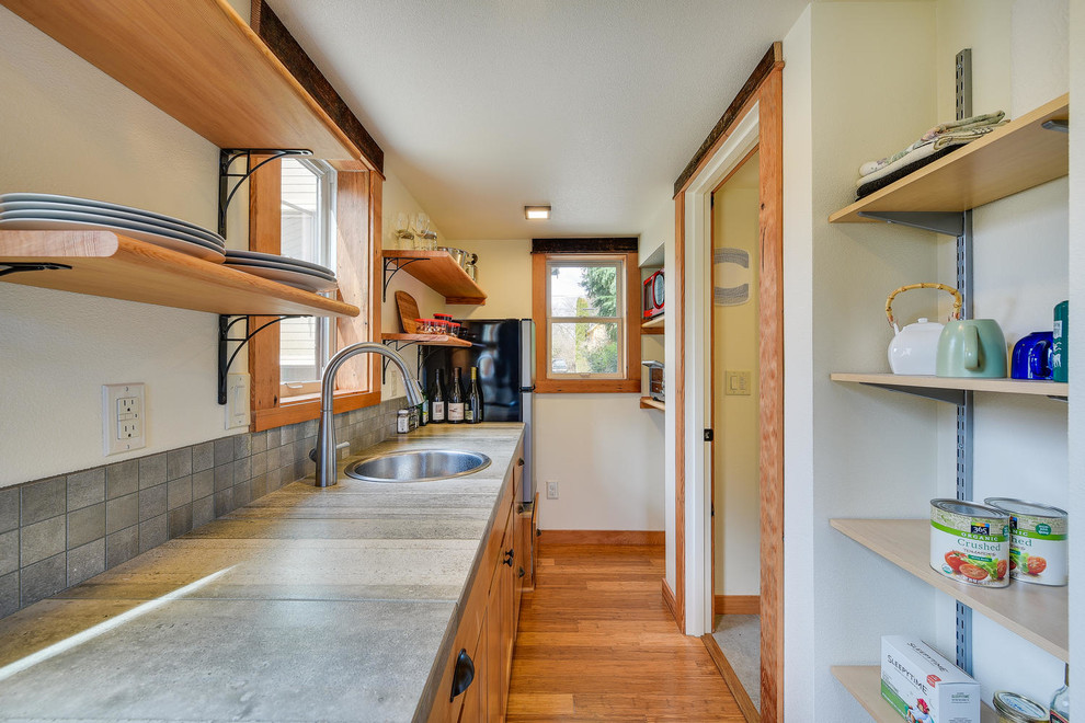 Photo of a small traditional galley eat-in kitchen in Portland with a drop-in sink, recessed-panel cabinets, medium wood cabinets, limestone benchtops, grey splashback, slate splashback, stainless steel appliances, medium hardwood floors, brown floor and grey benchtop.