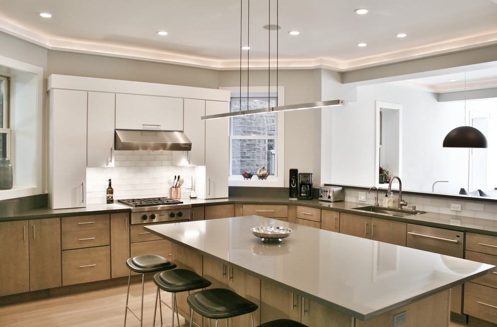 Kitchen - large transitional u-shaped light wood floor kitchen idea with an undermount sink, flat-panel cabinets, medium tone wood cabinets, quartz countertops, white backsplash, subway tile backsplash, stainless steel appliances and an island
